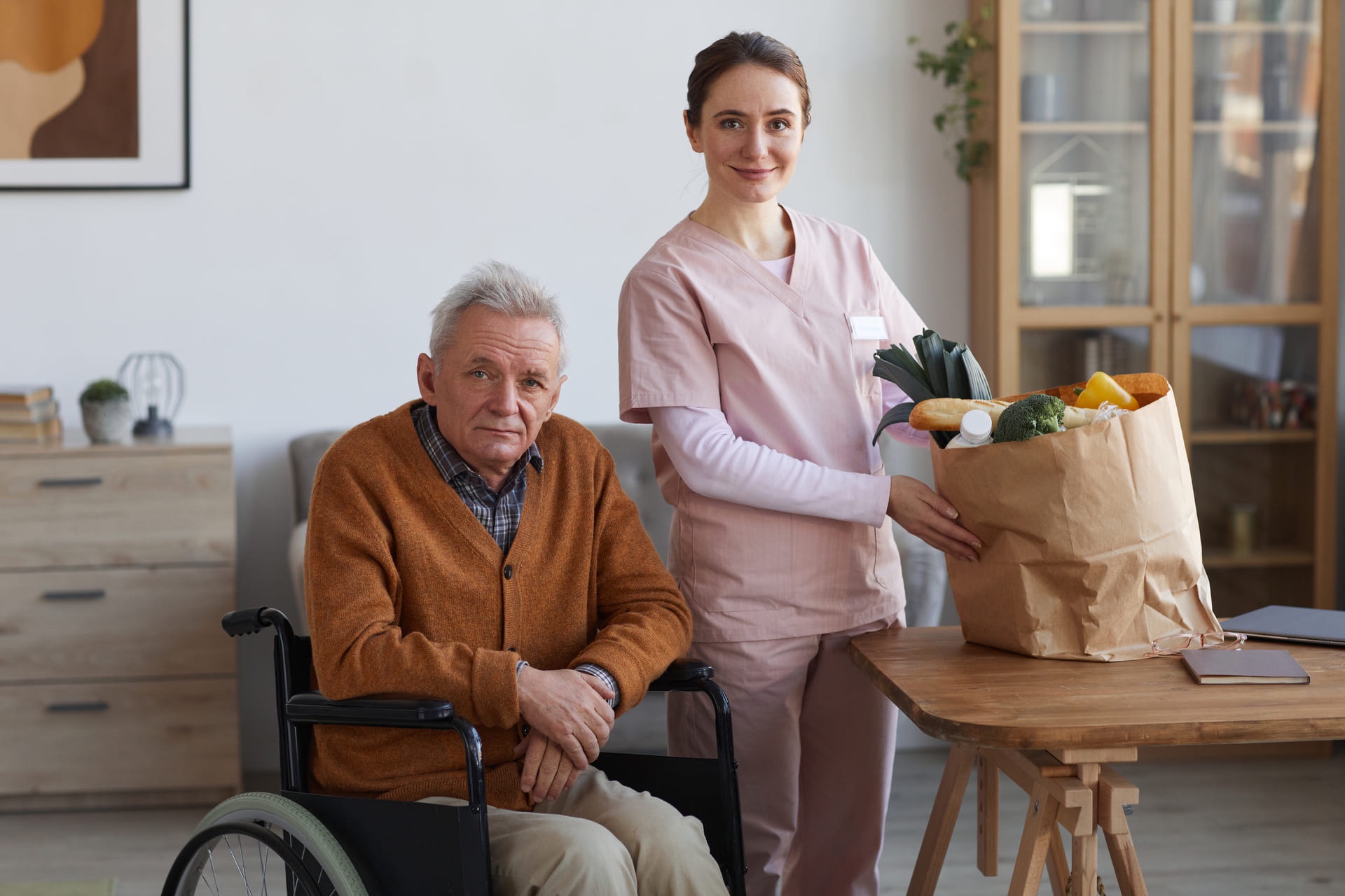 Alltagshelferin von Schöner Leben bringt einem älteren Mann zuhause den Einkauf